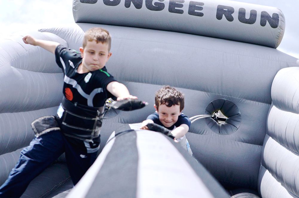 young boys playing in an inflatable game at an outdoor summer event