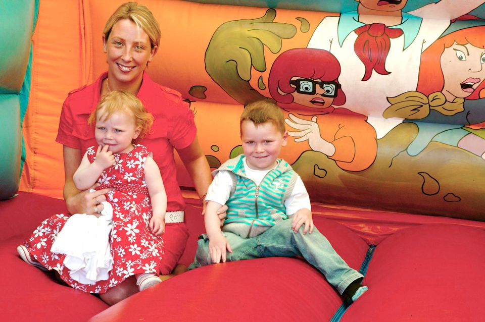 happy young family on an inflatable bouncy castle at a summer party
