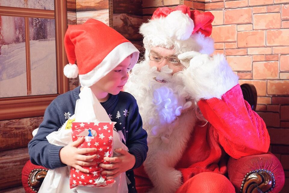 Santa in his grotto with a happy child at a Christmas event