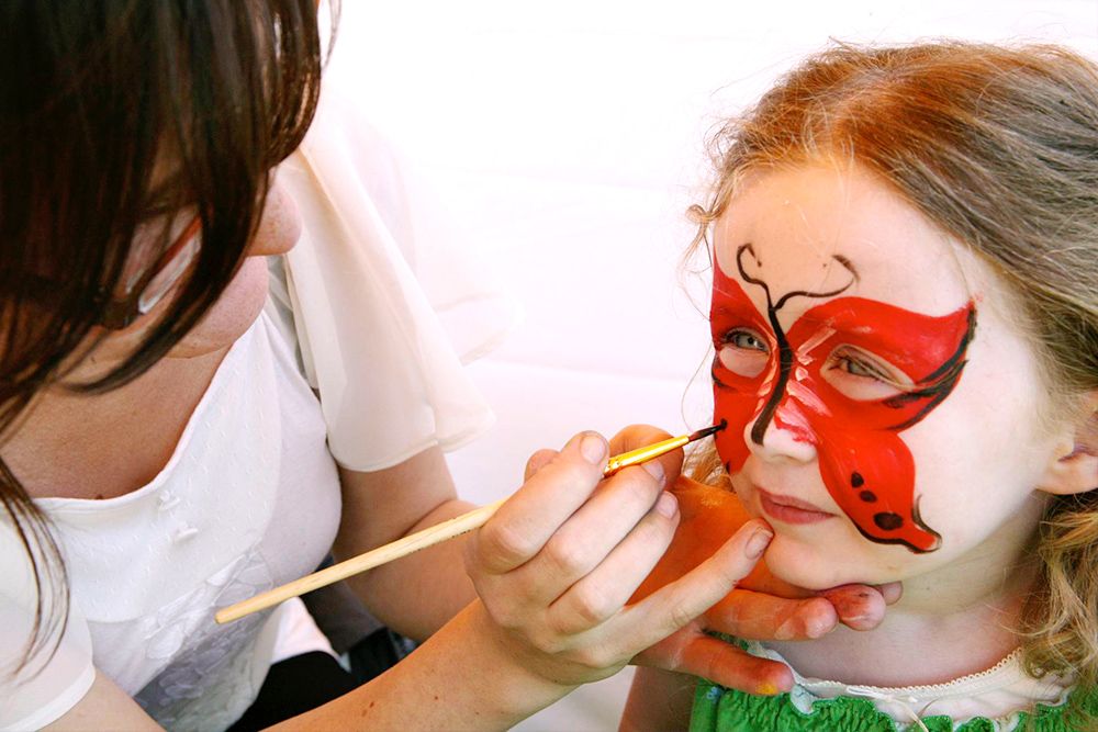 photo of a young girl having her face painted at a kids party