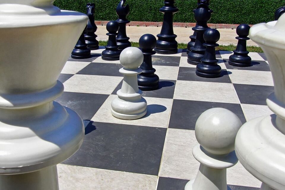 giant chess pieces on a giant chess board outside