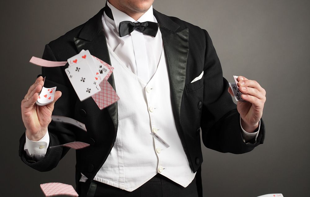 a magician entertainer in a suit performs his card trick at an event
