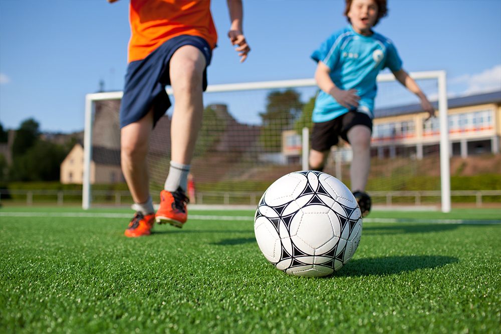 kids chasing and running after a soccer ball at an outdoor family sports event