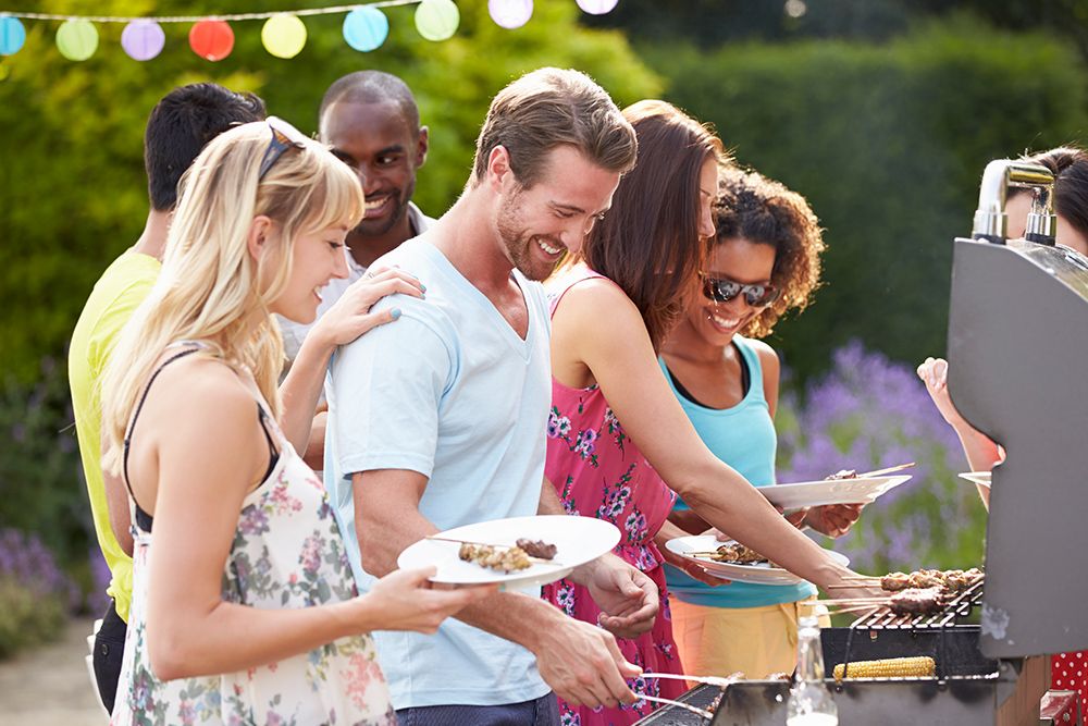 adults enjoying grilled food at an outdoor family summer event