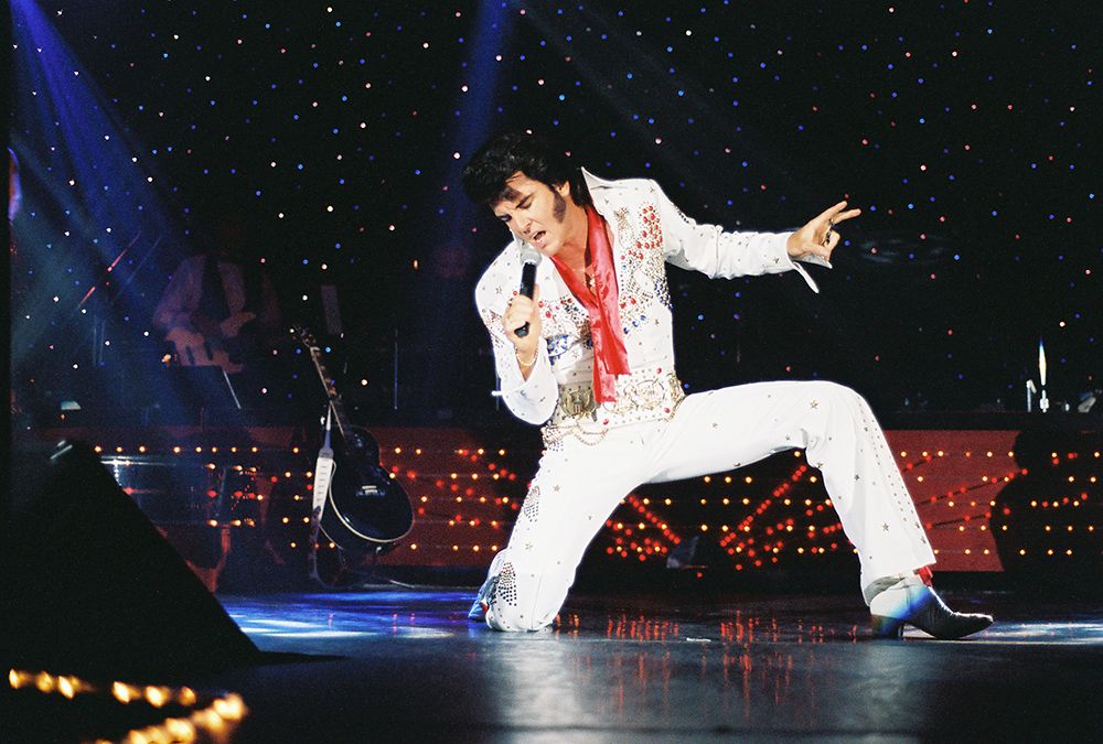 an Evis impersonator performs on stage at a las vegas themed corporate function